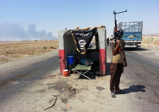 An al-Qaida-inspired militant stand guard at a checkpoint captured from the 
Iraqi Army outside Beiji refinery, some 150 miles north of Baghdad on 
Thursday. AP PHOTO