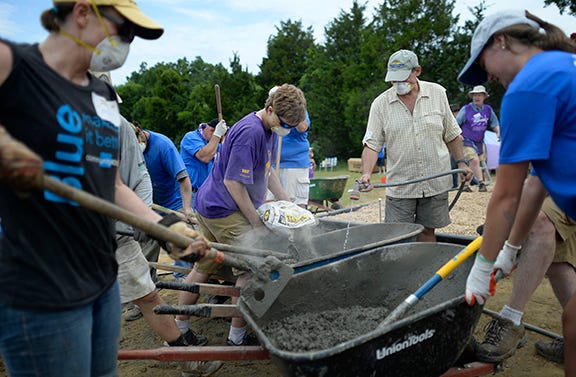 Volunteers mix concrete in a long line of wheelbarrows as they build a large playground in one day at Peacehaven Community Farm in Whisett, N.C. on Saturday, June 21, 2014. Photo by Scott Muthersbaugh.