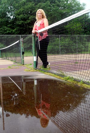Killingly Recreation Director Tracy Waggoner stands on a tennis court at Owen Bell Park in Dayville, where standing water has pooled around the net. A planned refurbishment of the park includes resurfacing damaged courts and tracks and building a new playscape.
