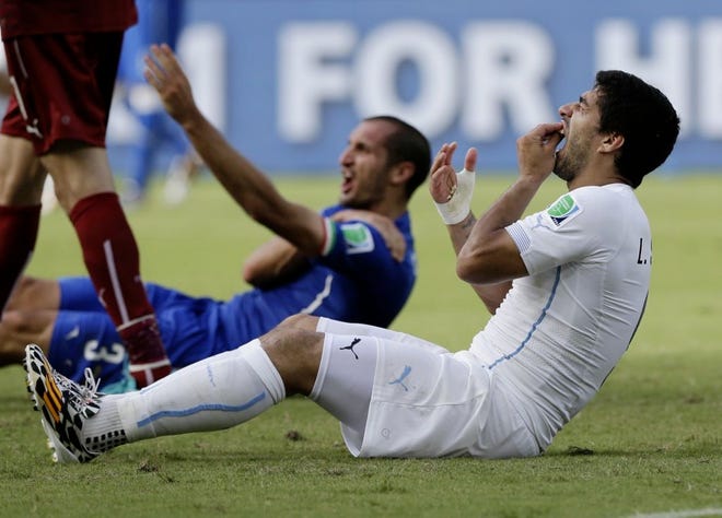 Uruguay's Luis Suarez holds his teeth after apparently biting the shoulder of Italy's Giorgio Chiellini, background, Tuesday during Uruguay's 1-0 victory in Natal, Brazil. The loss eliminated Italy from the World Cup and sent Uruguay to the second round.