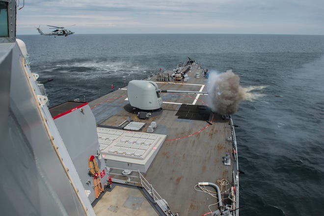 The 5-inch lightweight gun aboard the guided-missile destroyer USS Oscar Austin (DDG 79) fires at a target as part of a gunnery exercise during Baltic Operations (BALTOPS) 2014. Hovering off the port bow is an MH-60R Seahawk helicopter assigned to the HSM-72 "Proud Warriors" who are home based at NAS Jacksonville.