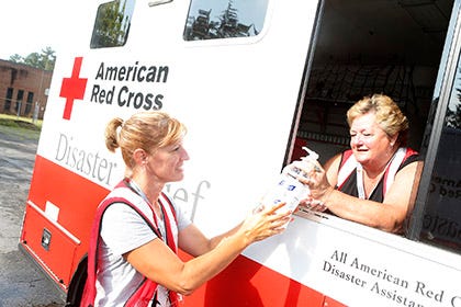 Cherril Welch passes a bottle of waterless hand sanitizer to Tammy Horne on a Red Cross vehicle Wednesday morning at Living Hope Community Church in Jacksonville, as they participated in a shelter simulation drill there, part of hurricane preparedness training.