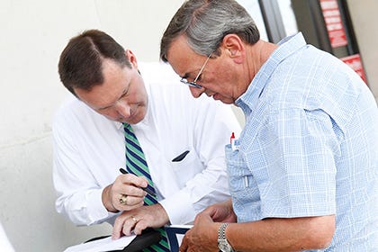Kevin McConnell goes over payment with highest bidder John Pierce following the auction for former Holly Ridge Smokehouse Restaurant on the front steps of Onslow County Superior Court in Jacksonville Wednesday afternoon.