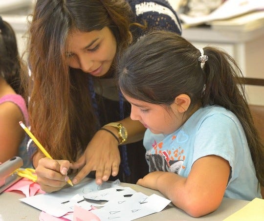 Marissa Cardoso, 17, a volunteer, helps Alicia Herrea, 7, with her art project during the Eloise Arts Center Summer Program on Wednesday.