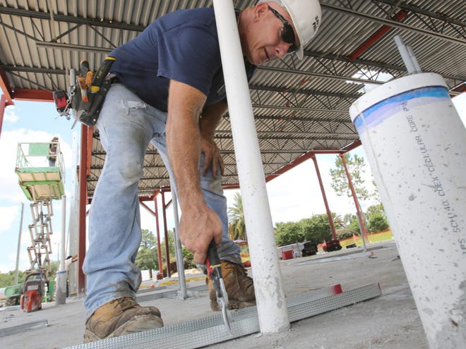 David Holmes of Advanced Drywall in Ocala cuts a piece of flashing as he works on the new Zaxby's that is under construction on S.E. Highway 441 in Belleview, Fla. on Tuesday, June 24, 2014. Construction on the more than 4,000 square foot restaurant is scheduled to be completed in 8 weeks. A Dunkin' Donuts, and an Ace Hardware store are also in the planning stages to be built in Belleview.