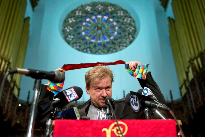 United Methodist pastor Frank Schaefer puts on a rainbow stole during a news conference Tuesday, June 24, 2014, at First United Methodist Church of Germantown in Philadelphia. Schaefer, who presided over his son's same-sex wedding ceremony and vowed to perform other gay marriages if asked, can return to the pulpit after a United Methodist Church appeals panel on Tuesday overturned a decision to defrock him. (AP Photo/Matt Rourke)