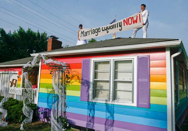Kimberly Kidwell, right, and her partner, Katie Short, of Arkansas, hold up a marriage equality sign on top of the Equality House before their wedding in June, 2013. Though Kidwell and Short's nuptuals aren't recognized by the state of Kansas, which bans same-sex marriage, a 10th Circuit Court of Appeals decision may change that, after the court struck down Utah's similar ban.