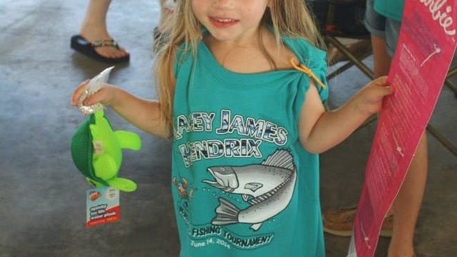 Delaney Saegert shows off prizes she won in the children’s tournament, as part of the James Kacey Hendrix Fishing Tournament.