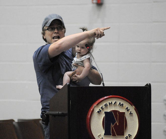 Drew Russo of Firebush Road holds daughter Leila, 6 months, as he talks about districting during the public comment section of the Neshaminy board meeting on Thursday night in the Maple Point Middle School auditorium.