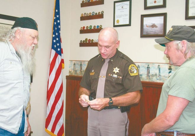 Cheboygan County Sheriff Dale Clarmont (middle) accepts two challenge coins from Vietnam veterans Duke Mayo (left) on behalf of the Vietnam Veterans of America Chapter 274 and Duane Swan (right) on behalf of the First Cavalry Division.