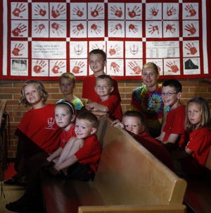 Students from the St. Paul Lutheran School sit in the sanctuary of the church in front of a quilt with their handprints. The school closed in May after declining enrollment and financial straits.