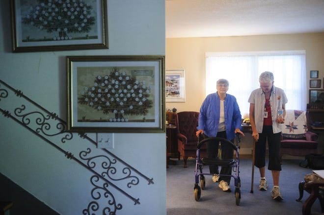 Kay Robertson, left, walks to the kitchen with Marianne Miller, a caregiver with Home Instead Senior Care, at Robertson’s home in Columbia.