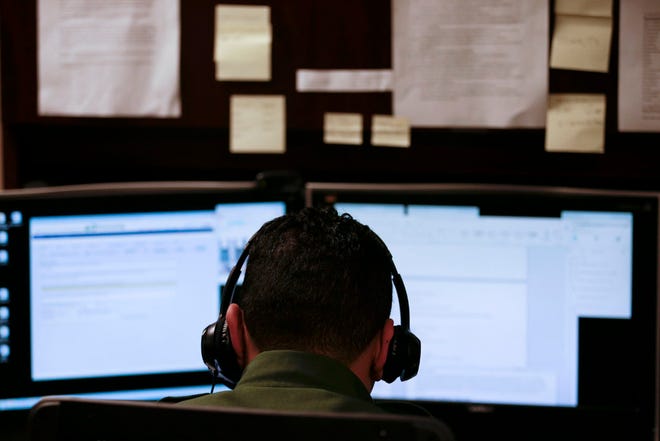 In this June 5, 2014 photo, a Border Patrol agent uses a headset and computer to conduct a long distance interview by video with a person arrested crossing the border in Texas, from a facility in San Diego.