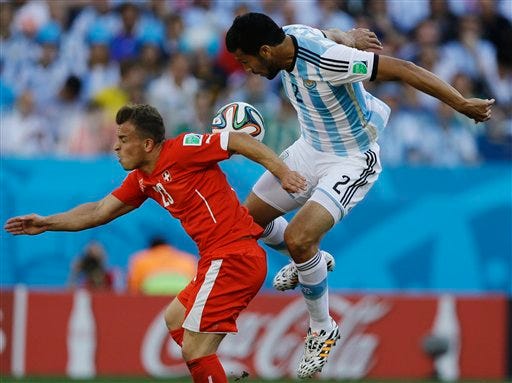 Switzerland's Xherdan Shaqiri, left, and Argentina's Ezequiel Garay go for a header during their World Cup round of 16 soccer match at the Itaquerao Stadium in Sao Paulo, Brazil, Tuesday, July 1, 2014. (AP Photo/Kirsty Wigglesworth)