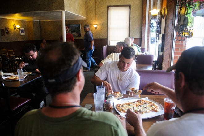 Austin Castle, center, eats pizza with his uncle Nathan Castle, left, and his father, Todd Castle, on June 20 at Tony’s Pizza Palace.