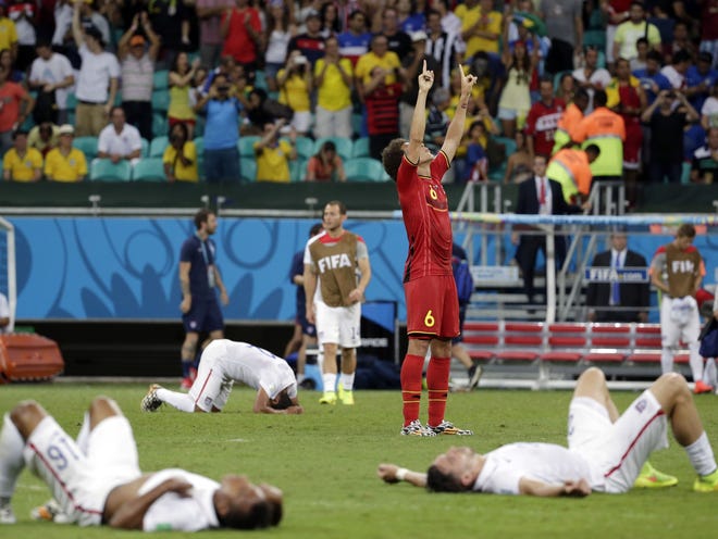 Exhausted US players lie on the ground as Belgium's Axel Witsel (6) celebrates at the end of the extra time during the World Cup round of 16 soccer match at the Arena Fonte Nova in Salvador, Brazil on Tuesday. Belgium held on to beat the United States 2-1 in extra time.