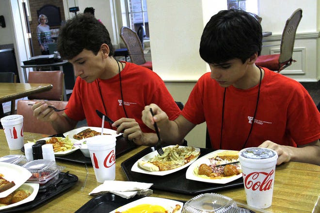Rodrigo Belonia, left, and João Turchetti, right, enjoy a meal provided by the TTUISD camp at Texas Tech on Tuesday. Tech will host a total of 180 students from Brazil this summer. (Brendan Bilbo/AJ Media)