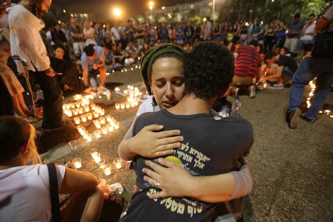 Israelis gather and light candles after the announcement that bodies of the three missing Israeli teenagers were found near the West Bank town of Hebron, Monday, June 30, 2014. The Israeli military found the bodies of three missing teenagers on Monday, just over two weeks after they were abducted in the West Bank, allegedly by Hamas militants. The grisly discovery culminated a feverish search that led to Israel's largest ground operation in the Palestinian territory in nearly a decade and raised fears of renewed fighting with Hamas. Israeli Prime Minister Benjamin Netanyahu was huddling with his Security Cabinet late Monday to discuss a response. (AP Photo/Yaron Brener) ISRAEL OUT