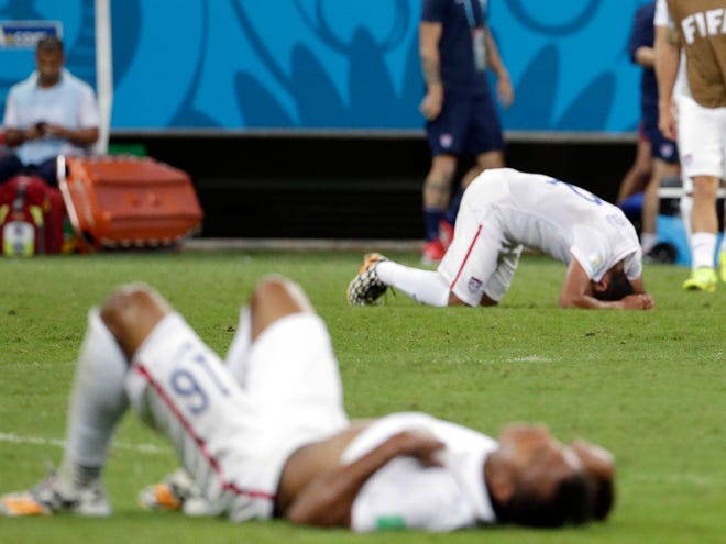 Exhausted US players lie on the ground as Belgium's Axel Witsel (6) celebrates at the end of the extra time during the World Cup round of 16 soccer match between Belgium and the USA at the Arena Fonte Nova in Salvador, Brazil, Tuesday, July 1, 2014. Belgium held on to beat US 2-1 in extra time.