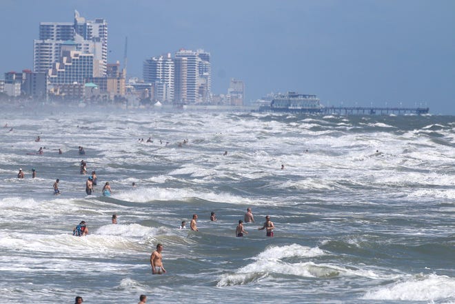 Beachgoers deal with high surf and currents off Daytona Beach generated Tuesday by Tropical Storm Arthur.