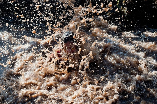 FILE - A competitor falls into a mud pit at Three Sisters Park in Chillicothe during the Hard Charge obstacle race in 2013. Hard Charge is folding operations and money intended for the Children's Hospital of Illinois is in question.