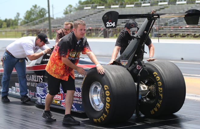 Josh Hart, foreground, owner of Burnyzz Speed Shop in Ocala, is among pit crew members pushing “Big Daddy” Don Garlits's electric dragster back to the line after a burnout at Bradenton Motorsports Park on June 8.