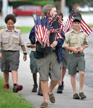 Ryan Garner, 16, leads members of Boy Scout Troop 35 with a bucket of flags en route to an Independence Day ceremony in Jacksonville, Fla.