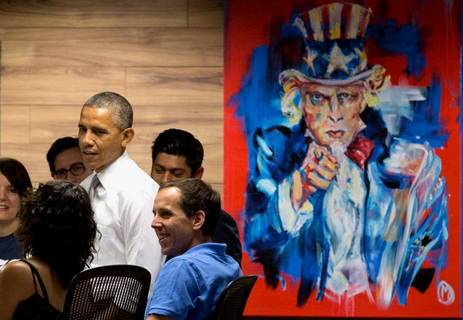 President Barack Obama stands next to a painting of "Uncle Sam," during a visit with workers at 1776, a hub for tech startups, Thursday, July 3, 2014, in Washington. The president said job growth in June shows the recovery is taking hold, but the economy could still do better, he also urged Congress to work with him to help create more jobs.