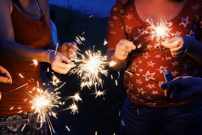From left, Marisha Brownell and her sister Madison Brownell light sparklers in Portsmouth on Saturday in honor of the Fourth of July weekend.