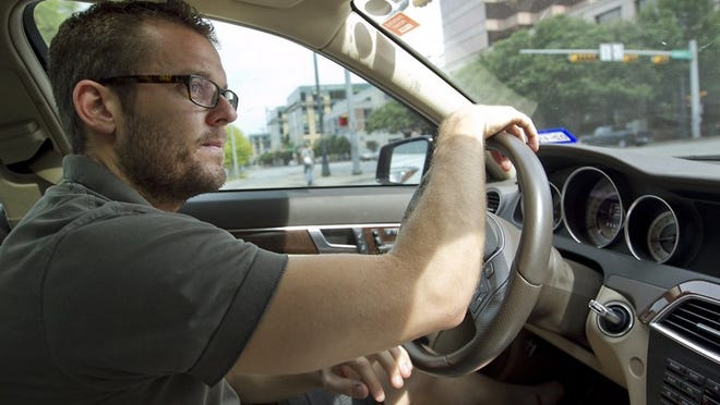Joe Stephens, seen in his car in downtown Austin, is a driver for Uber, a mobile app that connects participating drivers with paying passengers. Stephens said he doesn’t worry too much about his insurance coverage.