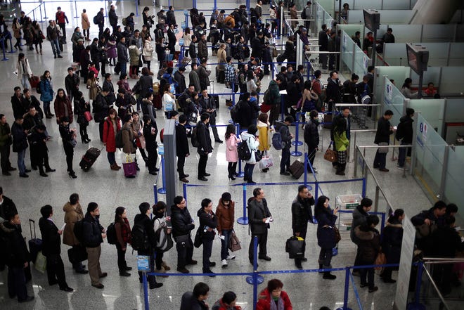 In this Jan. 20, 2012, file photo, passengers queue up for a security check at Pudong International Airport in Shanghai, China.