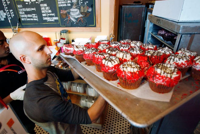 FILE - In this Sept. 20, 2007 file photo, Crumbs Bake Shop managing partner Harley Bauer carries of tray of cupcakes during the store's grand opening in Beverly Hills, Calif. Crumbs on Monday, July 7, 2014 shuttered all its stores, a week after the struggling cupcake shop operator was delisted from the Nasdaq.