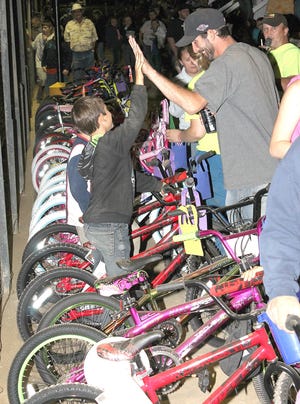 The celebration of winning a new bike a father and son high-five each other after winning a bicycle during Saturday's Josh Hadley Memorial race and bike giveaway at Butler Motor Speedway. ANDY BARRAND PHOTO