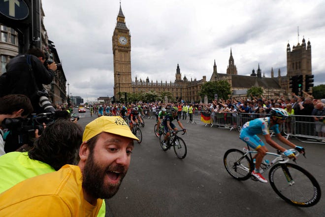 A cycling fan celebrates as the pack passes the Houses of Parliament in central London, during the third stage of the Tour de France cycling race over 155 kilometers (96.3 miles) with start in Cambridge and finish in London, England, Monday, July 7, 2014. (AP Photo/Lefteris Pitarakis)