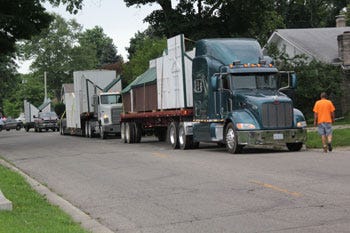 Trucks from Pueschel Farms bring Safety Town buildings to Wall School from Sturgis High School last week.