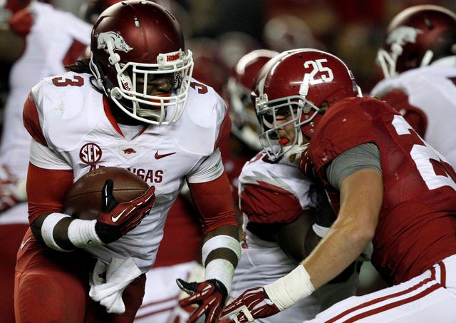 Arkansas running back Alex Collins (3) tries to get around Alabama linebacker Dillon Lee (25) as he carries the ball during the second half of an NCAA college football game on Saturday, Oct. 19, 2013, in Tuscaloosa, Ala. (AP Photo/Butch Dill)