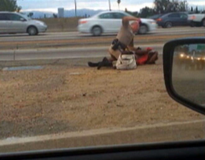 In this July 1, 2014 image made from video provided by motorist David Diaz, a California Highway Patrol officer straddles a woman while punching her in the head on the shoulder of a Los Angeles freeway. The woman had been walking on Interstate 10 west of downtown Los Angeles, endangering herself and people in traffic, and the officer was trying to restrain her, according to a CHP assistant chief. The officer, who has not been identified, has been placed on administrative leave during an investigation.