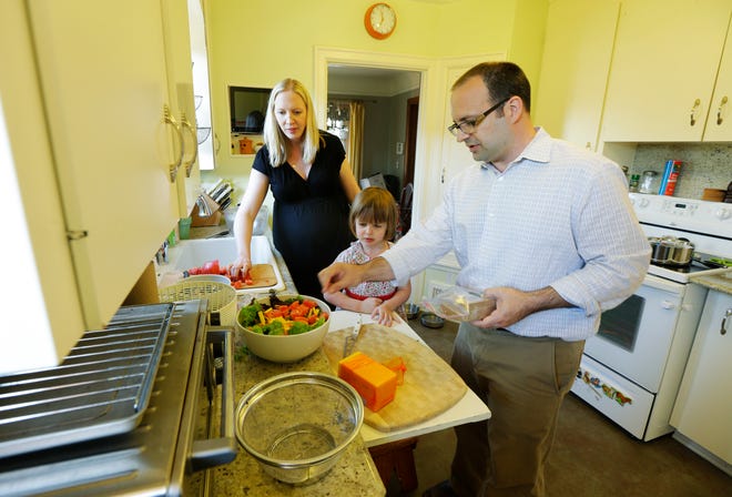 In this July 2, 2014 photo, Ryan Carson, right, cooks dinner with his wife, Jenny Roraback-Carson, left, and their daughter Clara, 3, at their home in Seattle. The Carsons are one of many would-be home sellers across the country who have mortgage rates so low, it doesn't make financial sense to sell their homes, even if they need more space, a trend which limits the supply of homes and can contribute to slower home sales.