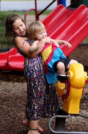 Jamie Mitchell • Times Record - Riley Shea, 8, gives her sister, Amelia Taff, 2, a lift onto the rocking duck, Thursday, July 10, 2014, while playing in the children's area at Carol Ann Cross Park. Amelia is the daughter of Jennifer and Robert Taff of Midland and Riley is the daughter of Guy Shea of Sugarloaf.
