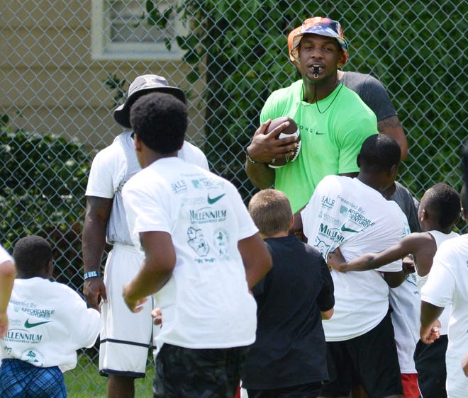 New York Jets linebacker and Kinston native Quinton Coples (center) is mobbed by children near the conclusion of Saturday’s QC Football Camp at Kinston High School.