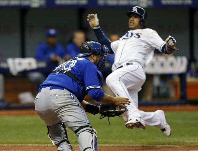 Toronto Blue Jays catcher Dioner Navarro waits for the throw as Tampa Bay Rays' Yunel Escobar slides in safely to score during the sixth inning of a baseball game Saturday, July 12, 2014, in St. Petersburg, Fla.