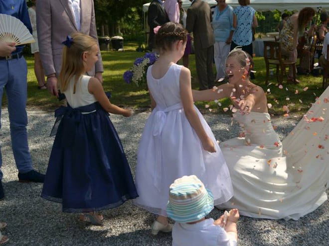 Bride Bailey is covered in rose petals by flower girls at her no-frills wedding.