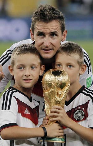 Germany's Miroslav Klose poses for a photo with his sons and the trophy after the World Cup final soccer match between Germany and Argentina at the Maracana Stadium in Rio de Janeiro, Brazil, Sunday, July 13, 2014. Germany won the match 1-0. (AP Photo/Matthias Schrader)