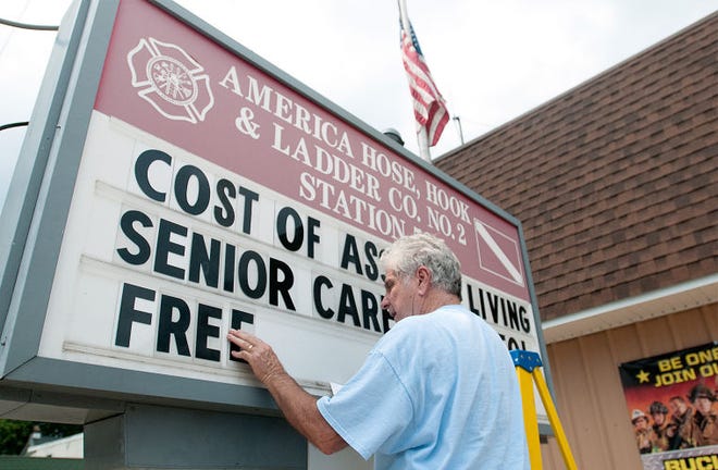 Chief Jim Mulholland of American Hose Hook and Ladder in Bristol changes the sign board outside of the station on Monday afternoon to say "Cost of Assisted Living, Senior Care of Bristol Free Seminar 07/15 6:30 for no charge for Senior Care of Bristol, which shares a building with the company. Mulholland can charge $50/week for someone to advertise on his board. The reverse of the board, which he was also changing, said "Mayor Sabatini don't risk the safety of our residents," referring to a recent controversy over fire-station funding in the borough.