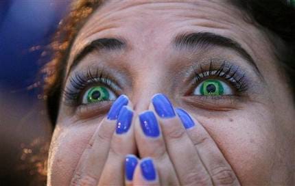 A Brazil soccer fan wearing contact lenses that mimic the Brazilian flag reacts as she watches her team play Germany in a World Cup semifinal game via live telecast inside the FIFA Fan Fest area on Copacabana beach in Rio de Janeiro, Brazil, Tuesday, July 8, 2014. (AP Photo/Leo Correa)