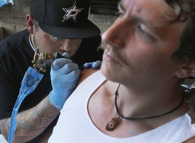 Tattoo artist Cody Biggs works on Adam Metzger at Taboo Tattoo in Dallas. When safety standards are followed, tattoos are usually trouble-free, but experts advise taking the time to research the tattoo parlor and consider your own health history.