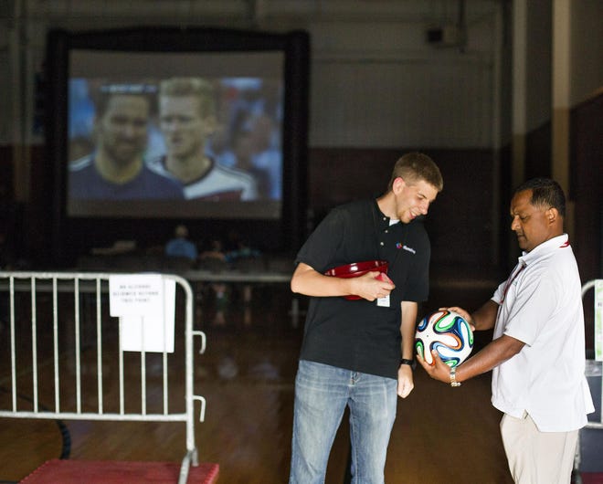 Willamalane program coordinator Josh Brandl (left) and Argentina fan Seve Ghose look at the soccer ball Josh is raffling off at the end of the Willamalane viewing party. Willamalane broadcast the game on two large screens, one in Spanish and the other in English. (Alisha Jucevic/The Register-Guard)
