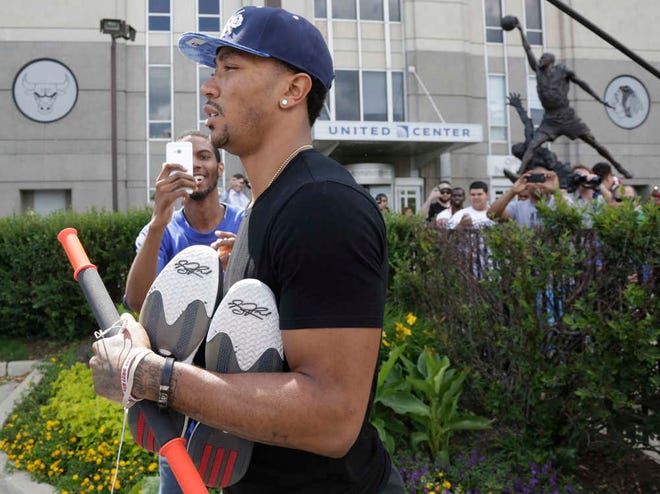 Chicago Bulls star Derrick Rose leaves the United Center after the Bulls met with NBA free agent Carmelo Anthony at the facility Tuesday, July 1, 2014, in Chicago. The Bulls believe they have a strong pitch and a simple selling point: Anthony can transform a playoff team into a championship contender. They believe uniting Anthony with Derrick Rose and Joakim Noah, who arrived earlier at the arena, would put them in position to contend for their first title since Jordan and Scottie Pippen led the way to two three-peats in the 1990s. (AP Photo/M. Spencer Green)