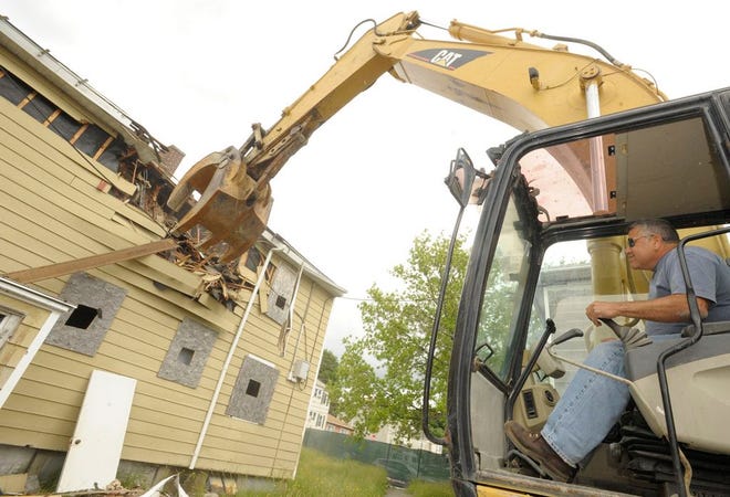 An AA Wrecking Company heavy equipment operator takes one of the first bites out of Watuppa Heights in June 2013.