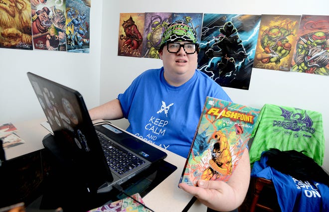 Arjay Floyd, 28, shows one of the comic books he recently started buying in his cosplay office Tuesday at his Crestview home. Floyd manages the website LivingfortheMoments.com, that fosters a community of cosplay enthusiasts.